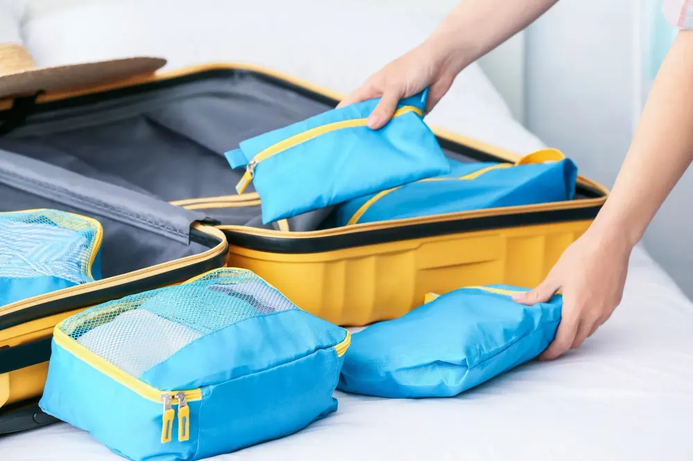Hands packing a suitcase full of packing cubes